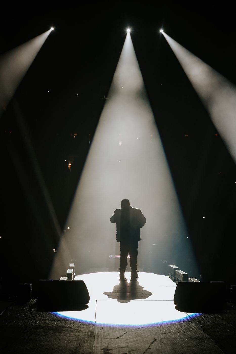 Silhouette of Mickael Guirand singing under a single spotlight