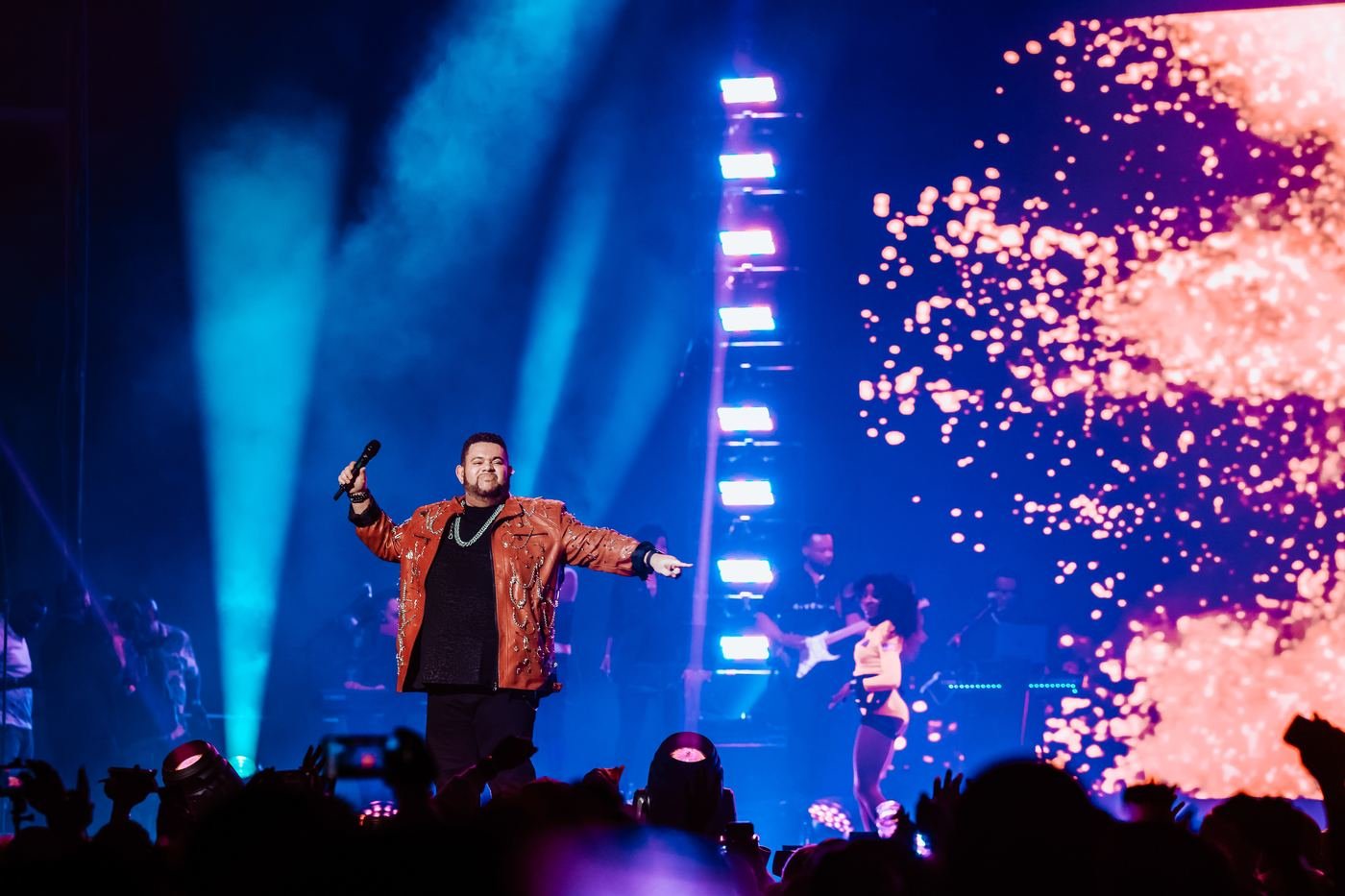 Mickael Guirand performing in an orange jacket with confetti falling