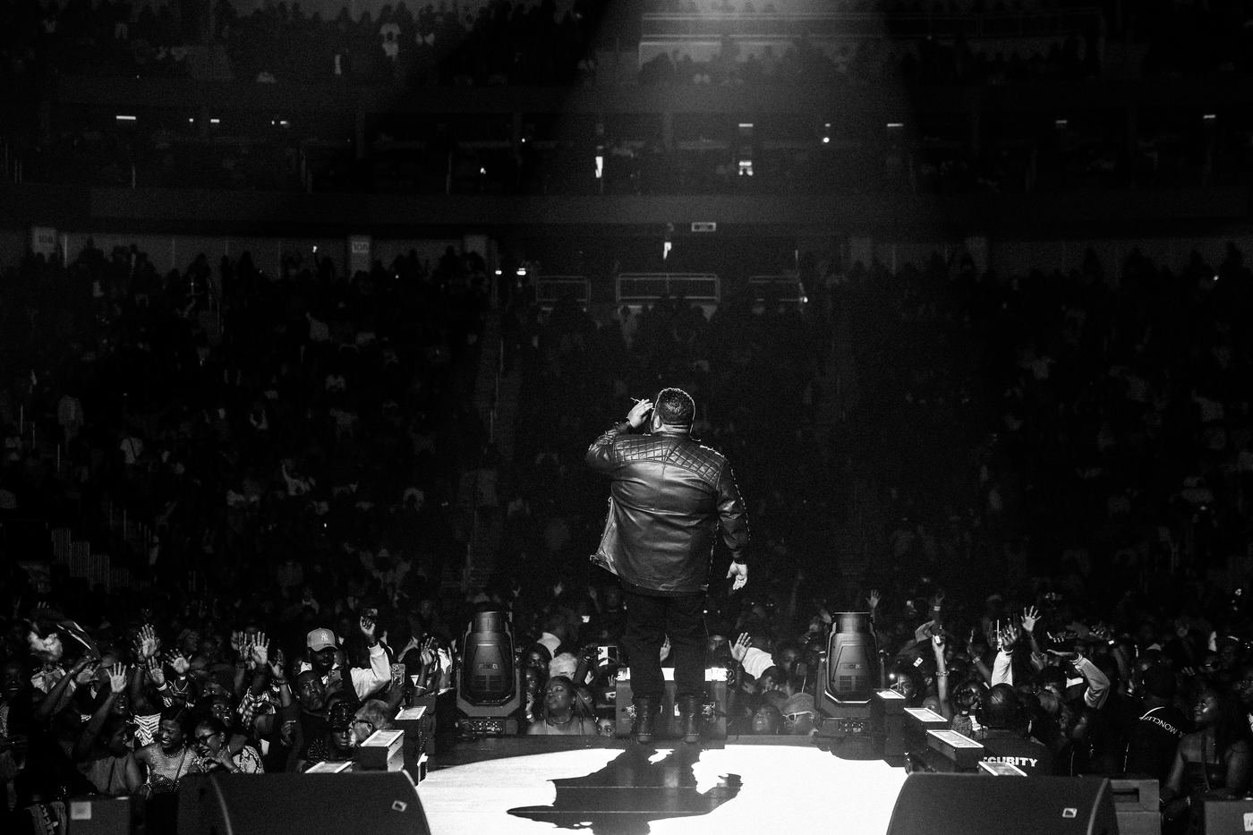 Black and white photo of Mickael Guirand facing the crowd from stage